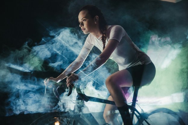 Woman cycling through misty atmosphere indoors