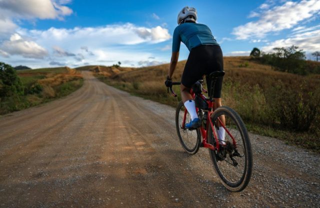 Cyclist biking on empty rural gravel road.