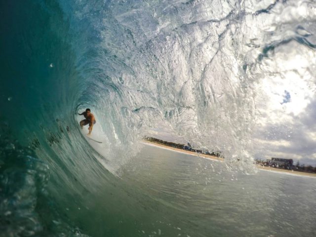 Surfer riding inside a powerful ocean wave barrel.