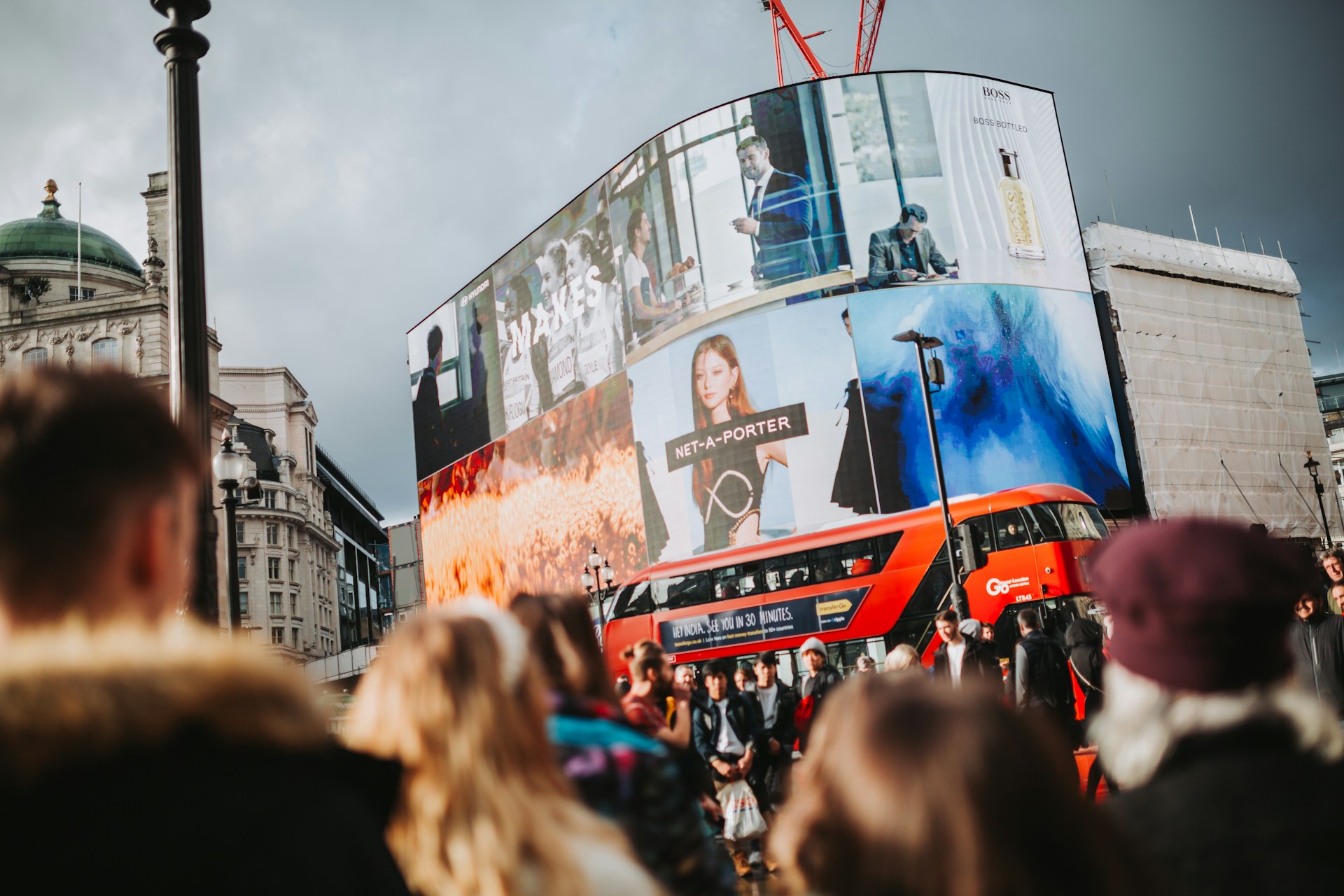 Crowd in front of large city LED billboards.