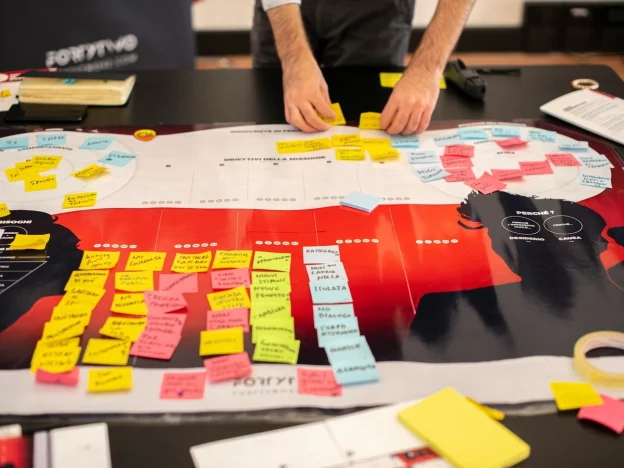 Person organizing sticky notes on a project board.