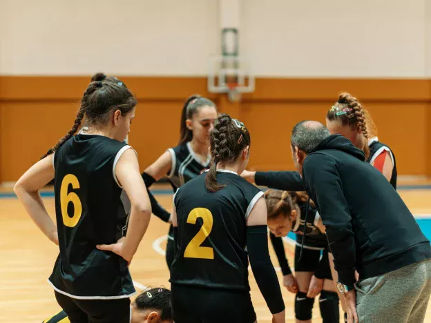 Coach and team huddle during basketball game.